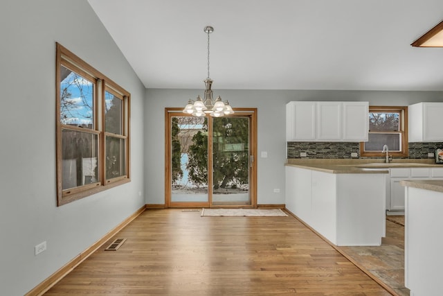 kitchen with backsplash, white cabinetry, a chandelier, and hanging light fixtures