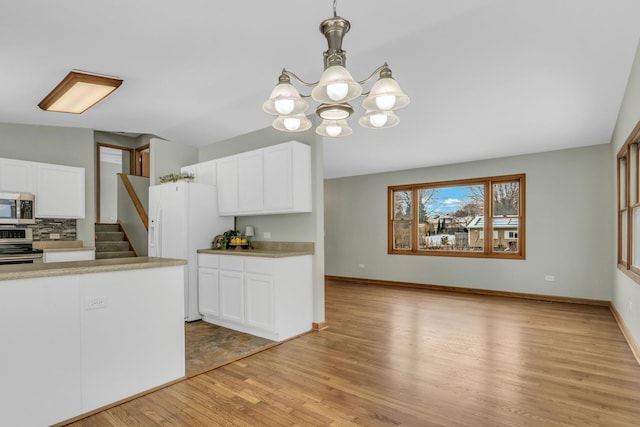 kitchen featuring appliances with stainless steel finishes, a chandelier, white cabinets, and hanging light fixtures