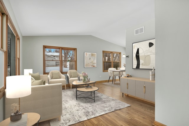 living room with light wood-type flooring and vaulted ceiling