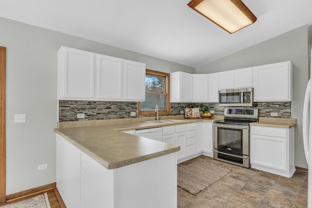 kitchen with vaulted ceiling, kitchen peninsula, sink, appliances with stainless steel finishes, and white cabinets