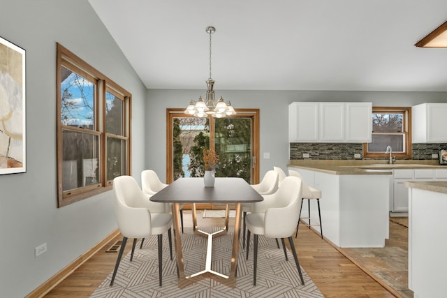 dining space with sink, lofted ceiling, a chandelier, and a healthy amount of sunlight