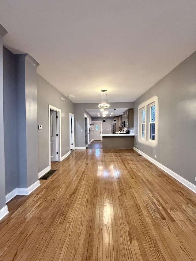 unfurnished living room with an inviting chandelier and hardwood / wood-style floors