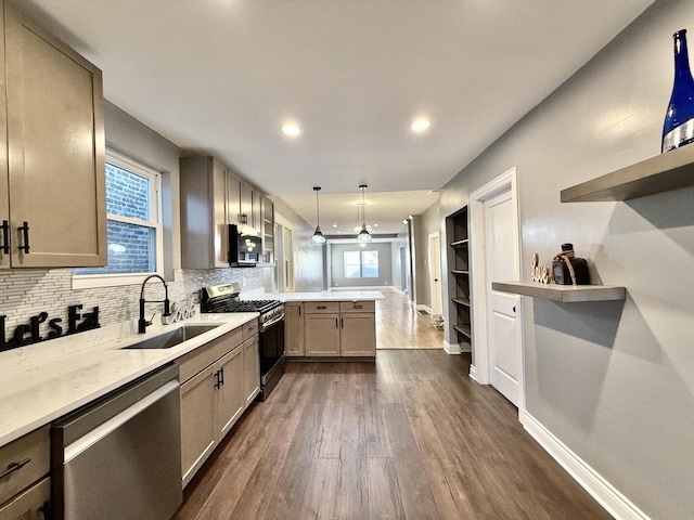 kitchen with kitchen peninsula, stainless steel appliances, dark hardwood / wood-style floors, hanging light fixtures, and sink