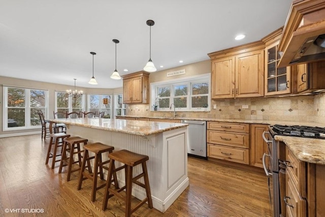 kitchen featuring a breakfast bar area, appliances with stainless steel finishes, hanging light fixtures, light stone counters, and a kitchen island