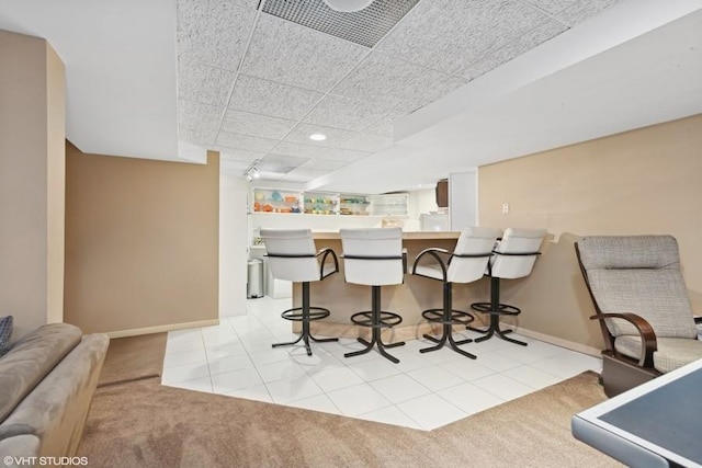 kitchen with a paneled ceiling, a kitchen breakfast bar, kitchen peninsula, and light carpet