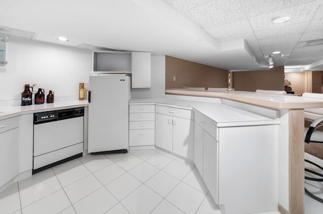 kitchen with white cabinets, a kitchen bar, light tile patterned floors, kitchen peninsula, and white appliances