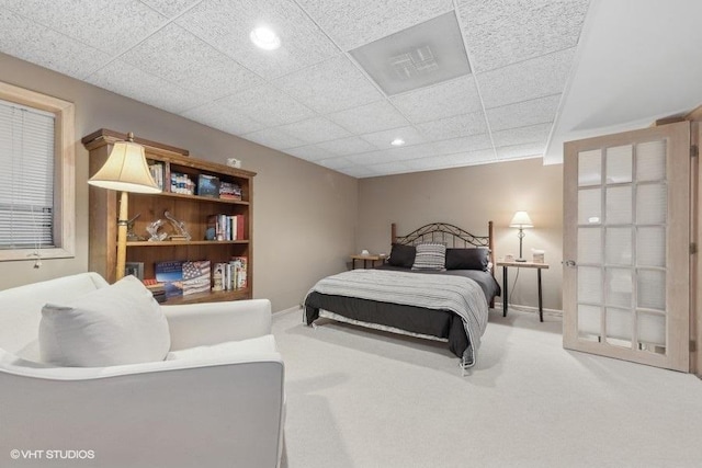 carpeted bedroom featuring a drop ceiling