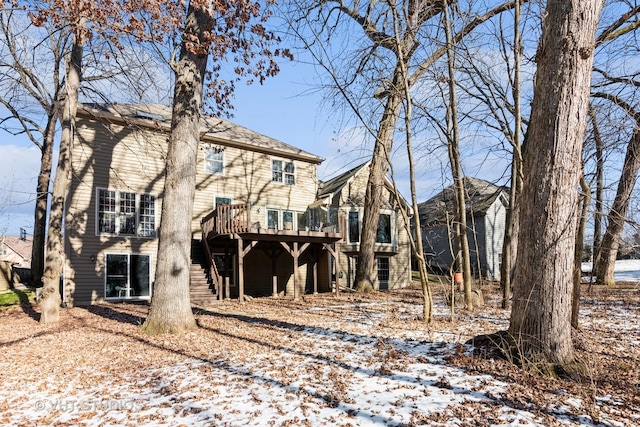 snow covered house featuring a wooden deck