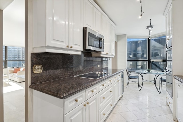 kitchen with white cabinetry, stainless steel appliances, tasteful backsplash, light tile patterned flooring, and dark stone counters