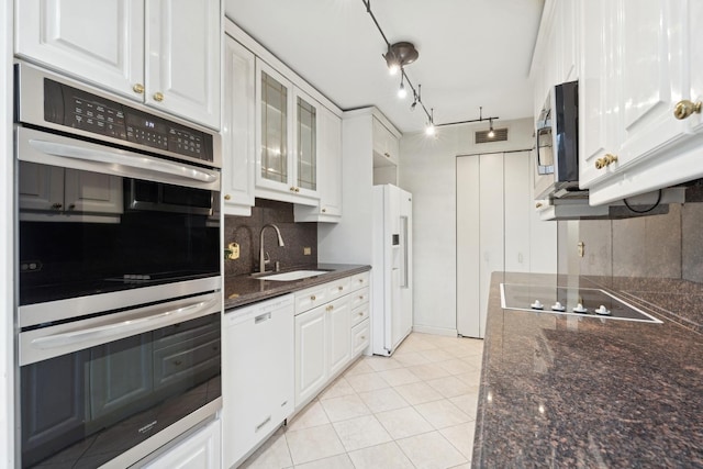 kitchen with light tile patterned floors, appliances with stainless steel finishes, backsplash, white cabinets, and sink