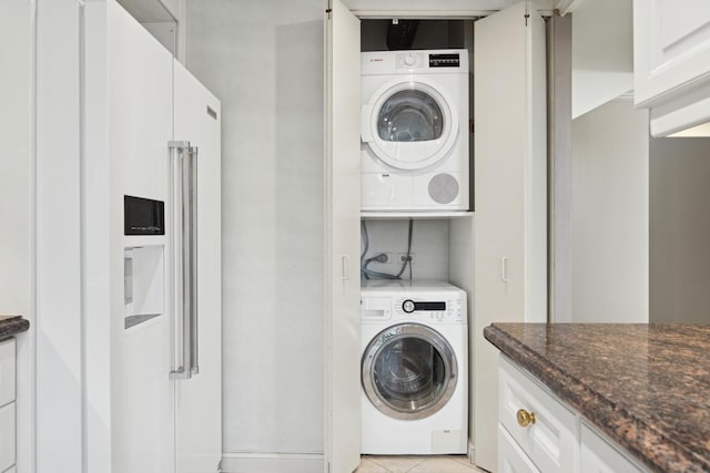 laundry room featuring stacked washer / drying machine and light tile patterned floors