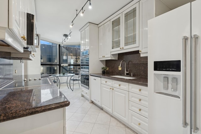 kitchen with white appliances, white cabinetry, decorative backsplash, sink, and light tile patterned flooring