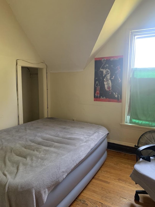 bedroom with vaulted ceiling and light hardwood / wood-style floors