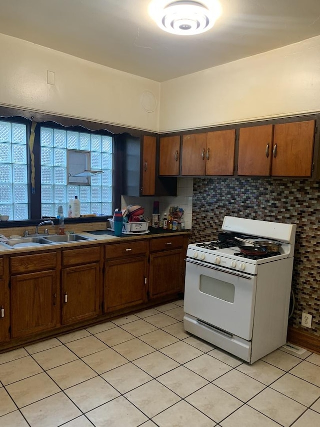 kitchen featuring white gas stove, tasteful backsplash, and sink