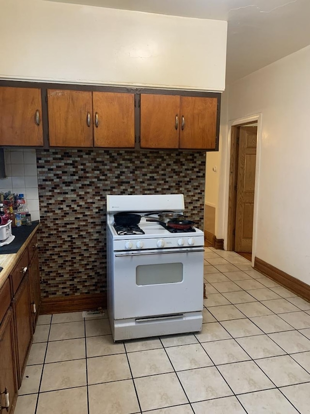 kitchen with backsplash, white range with gas cooktop, and light tile patterned flooring