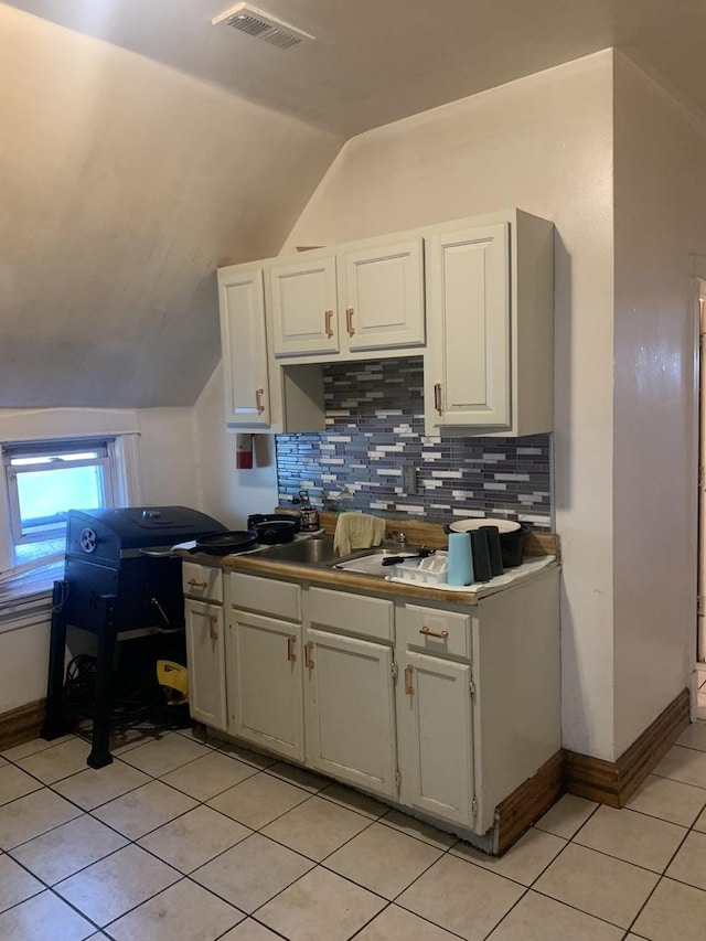 kitchen with decorative backsplash, light tile patterned floors, white cabinets, and lofted ceiling