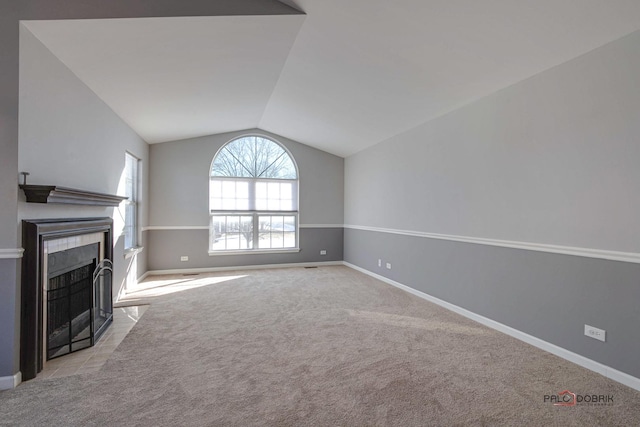 unfurnished living room featuring lofted ceiling, light colored carpet, and a tiled fireplace