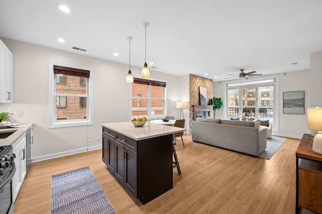 kitchen featuring a fireplace, decorative light fixtures, white cabinetry, a kitchen bar, and a center island