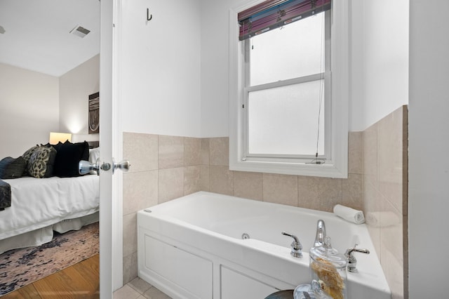 bathroom with tile patterned flooring, a tub, and tile walls