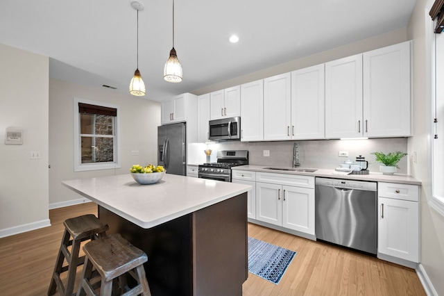 kitchen with pendant lighting, sink, white cabinets, and appliances with stainless steel finishes