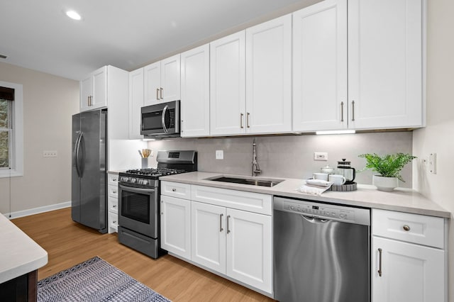 kitchen with white cabinetry, appliances with stainless steel finishes, sink, and light wood-type flooring