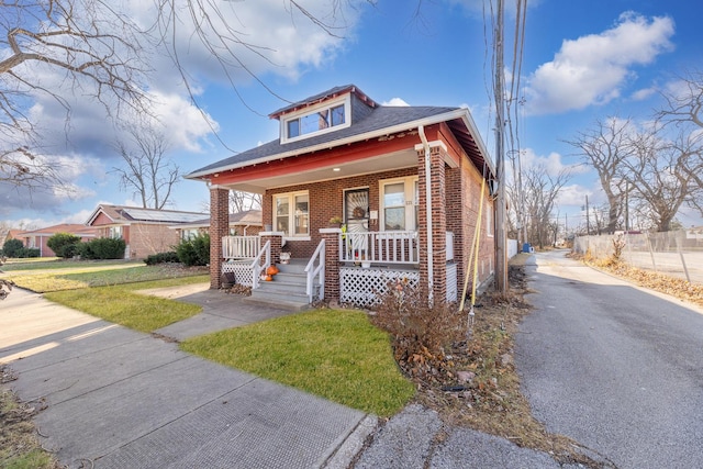 bungalow-style home featuring covered porch and a front lawn