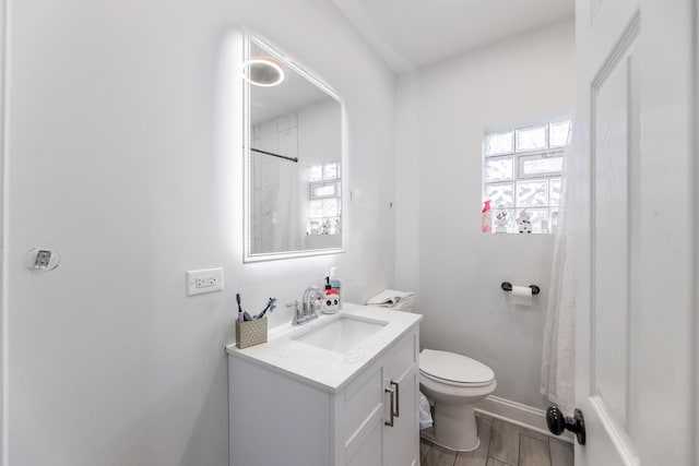 bathroom featuring toilet, walk in shower, and vanity