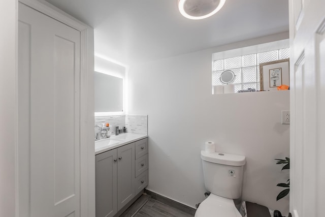 bathroom with wood-type flooring, backsplash, toilet, and vanity