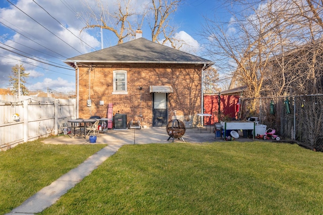 rear view of house with central AC, a yard, a patio, and a fire pit