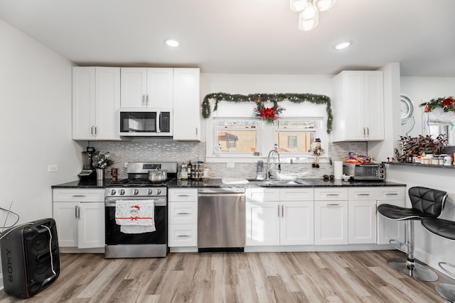 kitchen with sink, white cabinetry, stainless steel appliances, and dark stone countertops