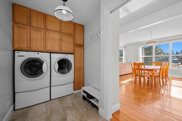 clothes washing area with plenty of natural light, cabinets, and washing machine and clothes dryer