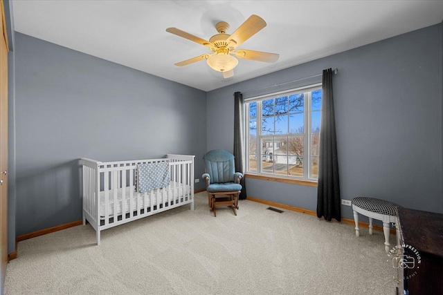 bedroom with a nursery area, ceiling fan, and carpet flooring