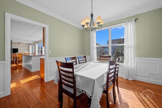 dining room with crown molding, an inviting chandelier, and light hardwood / wood-style flooring