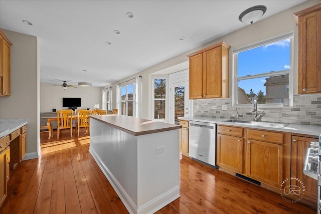 kitchen with hardwood / wood-style floors, sink, decorative backsplash, a center island, and stainless steel dishwasher