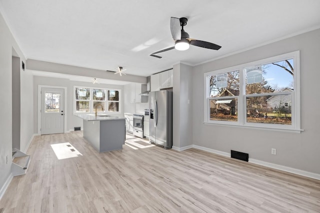 kitchen featuring white cabinetry, light hardwood / wood-style floors, a center island with sink, ceiling fan, and appliances with stainless steel finishes