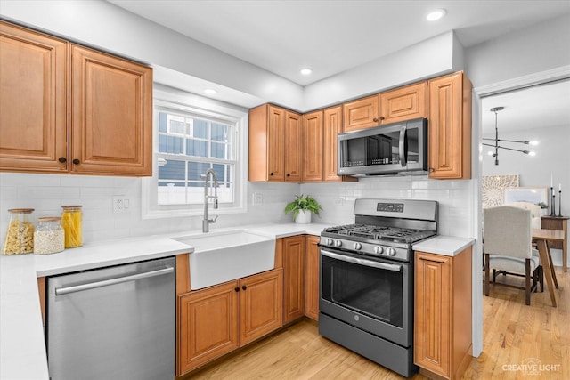 kitchen with sink, backsplash, light hardwood / wood-style flooring, and stainless steel appliances