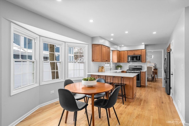 kitchen featuring black refrigerator, gas range, a kitchen breakfast bar, kitchen peninsula, and backsplash