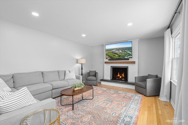 living room with light hardwood / wood-style floors and a brick fireplace