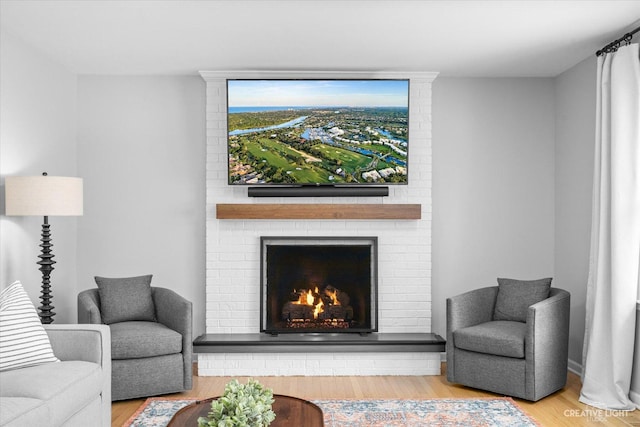 living room featuring wood-type flooring and a brick fireplace