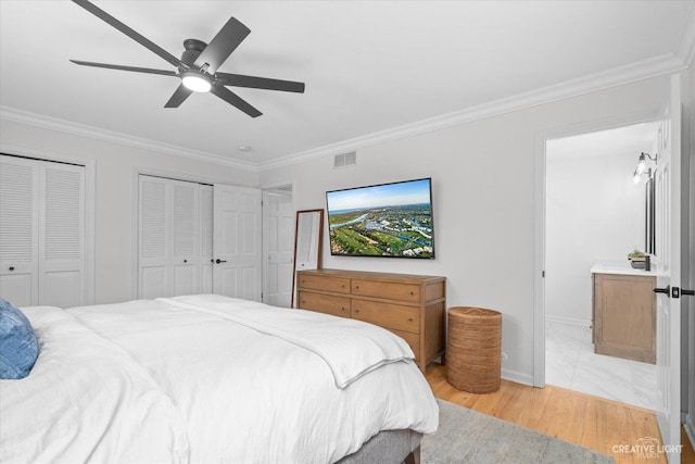 bedroom featuring crown molding, light hardwood / wood-style flooring, two closets, and ceiling fan