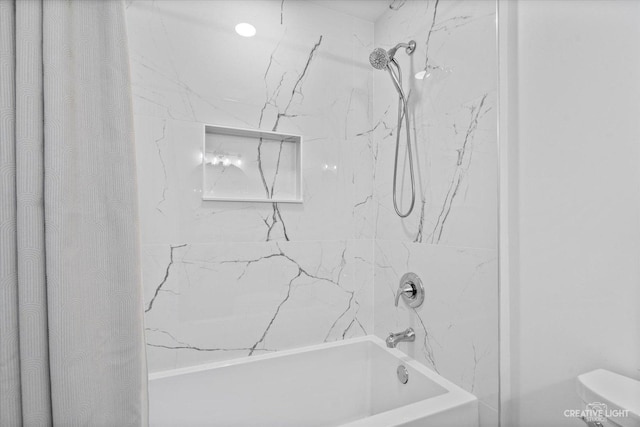 bathroom featuring toilet and tiled shower / bath