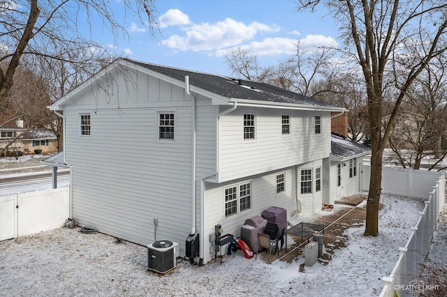 snow covered rear of property featuring central air condition unit