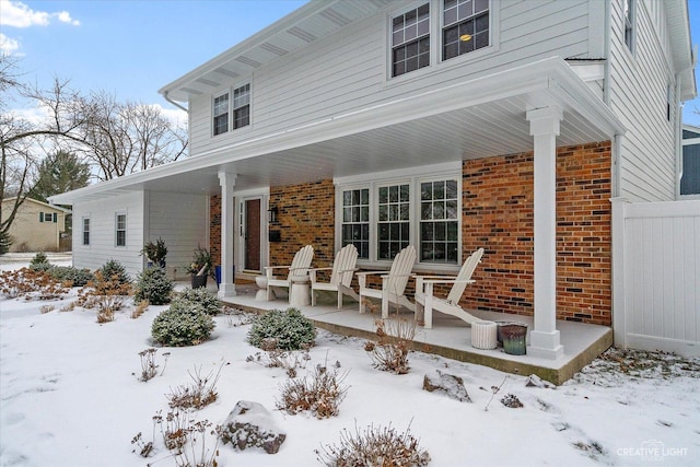 snow covered back of property featuring a porch