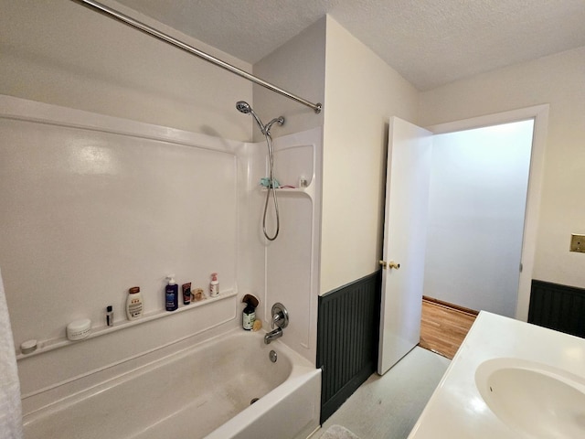 bathroom featuring a textured ceiling, bathtub / shower combination, and vanity