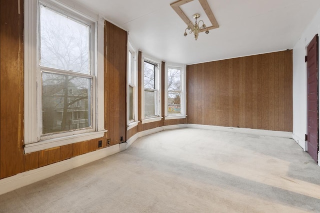 interior space featuring carpet floors, wood walls, and a notable chandelier