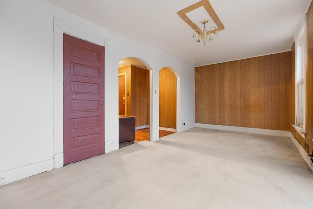 carpeted spare room with wooden walls