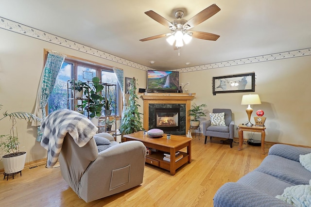 living room with a premium fireplace, light hardwood / wood-style floors, and ceiling fan