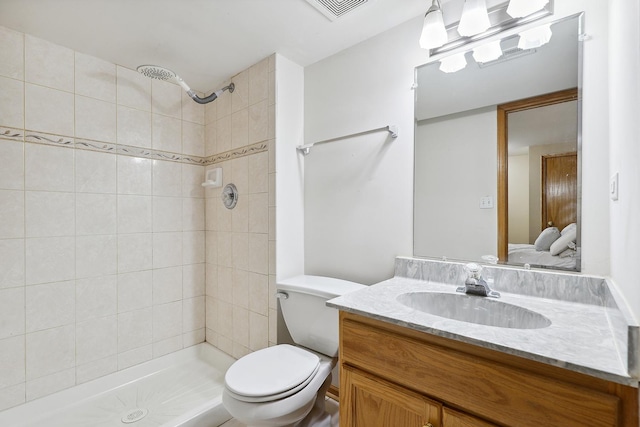 bathroom with vanity, a tile shower, and toilet