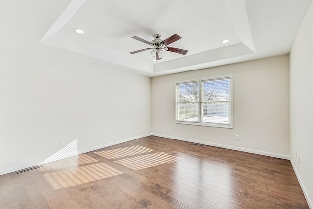 spare room featuring a raised ceiling, ceiling fan, and hardwood / wood-style floors