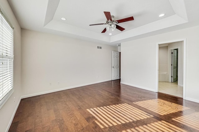 spare room featuring ceiling fan, dark hardwood / wood-style flooring, and a tray ceiling